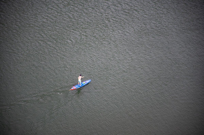 Paddle gonflable bleu et rouge vu de haut sur l'eau – Nautiya